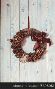 Natural eco Christmas wreath hanging on vintage blue wall. Natural eco Christmas wreath