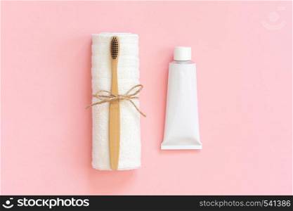 Natural eco-friendly bamboo brush on white towel and toothpaste tube. Set for washing on paper pink background. Close up, Copy space for text or your design Top view Flat lay.. Natural eco-friendly bamboo brush on white towel and toothpaste tube. Set for washing on paper pink background. Close up, Copy space for text or your design Top view Flat lay