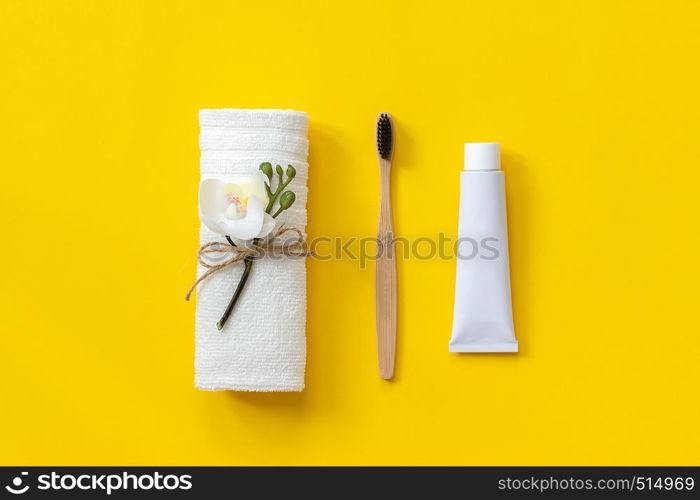 Natural eco-friendly bamboo brush, white towel and tube of toothpaste. Set for washing on paper yellow background. Copy space for text or your design Top view Flat lay.. Natural eco-friendly bamboo brush, white towel and tube of toothpaste. Set for washing on paper yellow background. Copy space for text or your design Top view Flat lay