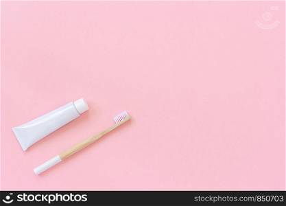 Natural eco-friendly bamboo brush with white bristles and tube of toothpaste. Set for washing on paper pink background. Copy space for text or your design Top view Flat lay.. Natural eco-friendly bamboo brush with white bristles and tube of toothpaste. Set for washing on paper pink background. Copy space for text or your design Top view Flat lay