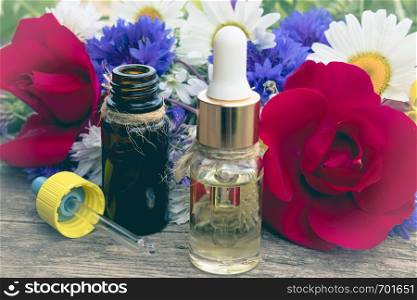 Natural essential oil with wild flowers on wooden background. Close-up.. Natural essential oil with wild flowers on wooden background.
