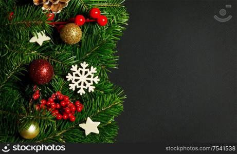 Natural fir Christmas tree border frame with decor on black, copy space for text. Fir tree and christmas decor
