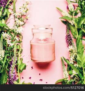Natural herbal skin care cosmetic concept. Glass jar with cream and fresh herbs and flowers on pink background, top view, copy space, square. Beauty, skin and hair care concept
