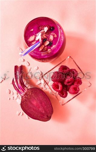 Natural ingredients for healthy smoothie from red vegetables and fruits, nuts in glass on a color background of the year 2019 Living Coral Pantone. Concept of vegan and healthy eating.. Fresh juicy detox smoothies in glass cup with red berries, beetroot on a color background of the year 2019 Living Coral Pantone. Top view.