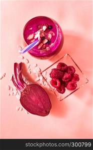 Natural ingredients for healthy smoothie from red vegetables and fruits, nuts in glass on a color background of the year 2019 Living Coral Pantone. Concept of vegan and healthy eating.. Fresh juicy detox smoothies in glass cup with red berries, beetroot on a color background of the year 2019 Living Coral Pantone. Top view.