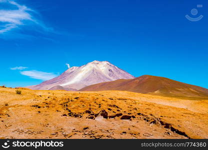 Natural landscape of active volcano Ollague at the Bolivia - Chile border with the smoke coming out of its crater