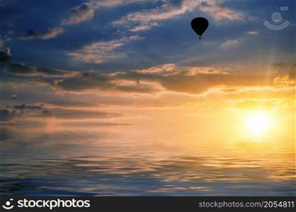 natural landscape with cloudy sky at sunset and air balloon reflected in water. sky and air balloon reflected in water