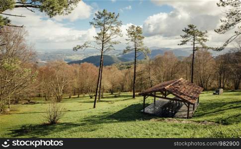 Natural landscape with gazebo in sunlight over cloudy sky and mountains background. Natural landscape with picnic area over nature background