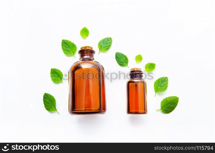 Natural Mint Essential Oil in a Glass Bottle with Fresh Mint Leaves on white over wooden background.