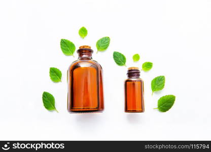 Natural Mint Essential Oil in a Glass Bottle with Fresh Mint Leaves on white over wooden background.