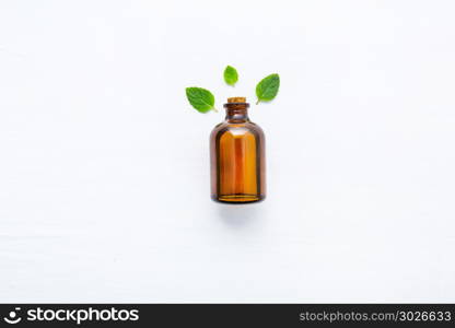 Natural Mint Essential Oil in a Glass Bottle with Fresh Mint Leaves on white background.