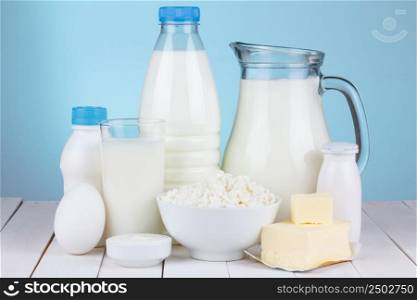 Natural organic dairy products, milk, cottage cheese, eggs, butter, yoghurt, butter and sour cream on white wooden bale and blue background still life