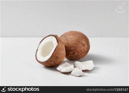 Natural organic set from fresh ripe coconut fruits with half and small pieces on a light grey duotone background, copy space. Vegetarian concept.. Composition from parts of fresh ripe natural coconuts fruits on a grey background.