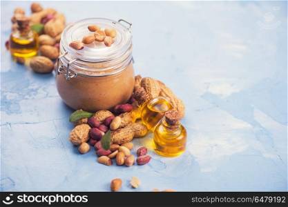 Natural peanut butter with oil in a glass jar and peanuts. Natural peanut butter. Natural peanut butter