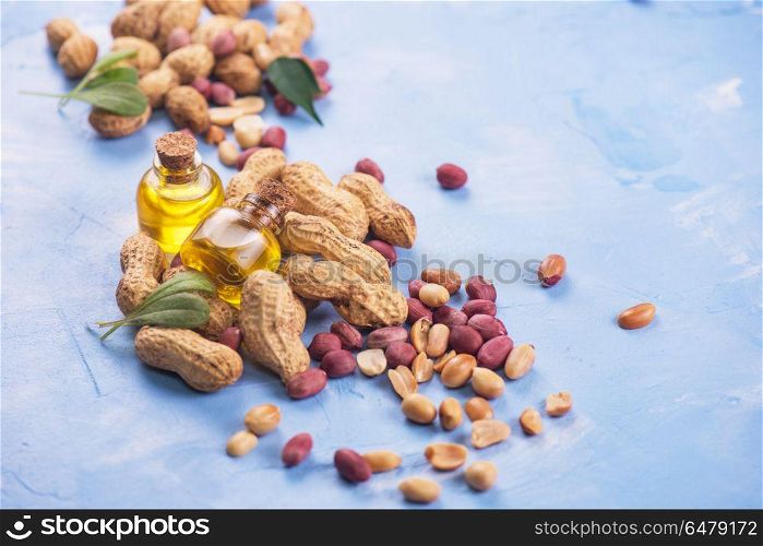 Natural peanut with oil in a glass. Natural peanuts with oil in a glass jar on the blue concrete background