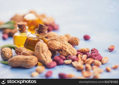 Natural peanut with oil in a glass. Natural peanuts with oil in a glass jar on the blue concrete background