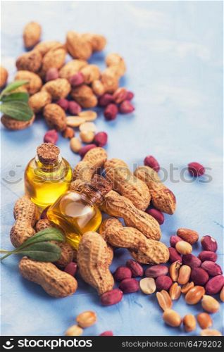 Natural peanut with oil in a glass. Natural peanuts with oil in a glass jar on the blue concrete background