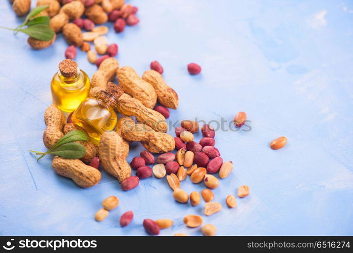 Natural peanut with oil in a glass. Natural peanuts with oil in a glass jar on the blue concrete background