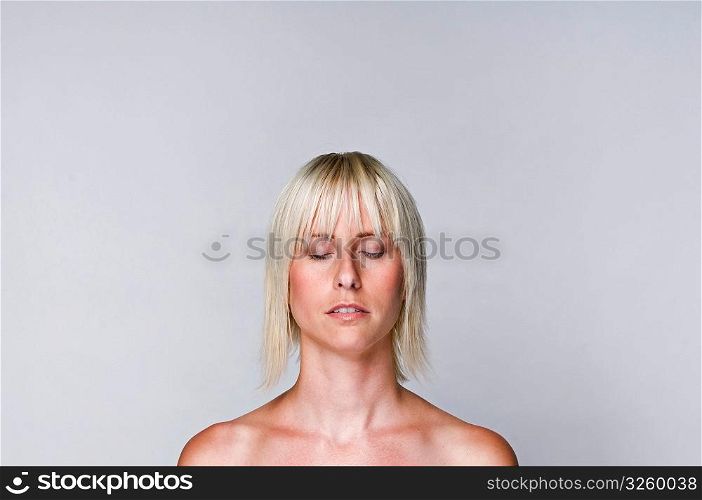 Natural portrait of an edgy blonde woman with her eyes shut.