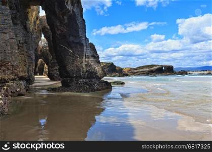Natural rock arches on Cathedrals beach in low tide (Cantabric coast, Lugo (Galicia), Spain). Peoples are unrecognizable.