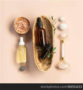 Natural SPA cosmetic products background, Composition with bottles of essential oils, sea salt and massage rollers on pink background, flat lay