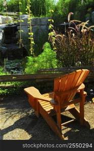 Natural stone pond and patio landscaping with wooden chair