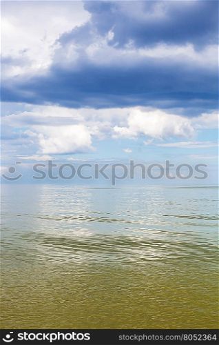 natural vertical background - Azov Sea waterscape with calm green water and blue sky with white and rain clouds. Temryuk bay, Golubitskaya resort, Taman peninsula, Kuban, Russia