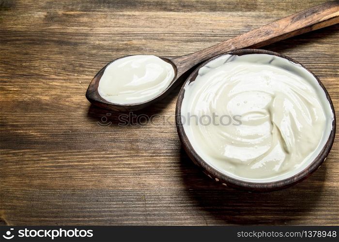 Natural yogurt in a bowl with a spoon. On a wooden table.. Natural yogurt in a bowl with a spoon.