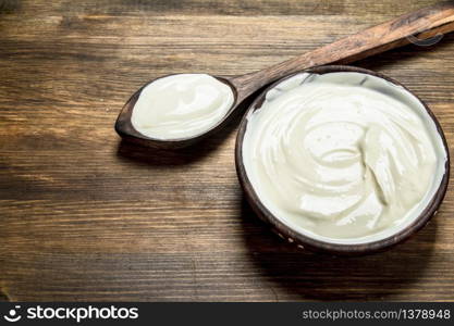 Natural yogurt in a bowl with a spoon. On a wooden table.. Natural yogurt in a bowl with a spoon.