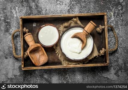 Natural yogurt with a scoop in a bowl. On a rustic background. Natural yogurt with a scoop in a bowl.