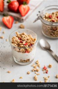 Natural yogurt with strawberry granola and fresh berries with spoon.