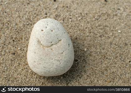 Naturally received image of smile on sea pebble stone on sand background