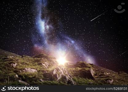 nature and astronomy concept - rocky landscape over night sky or space with shooting stars background. rocky landscape over night sky or space