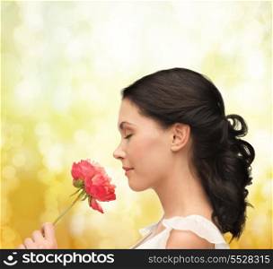 nature and beauty concept - smiling woman smelling flower with eyes closed
