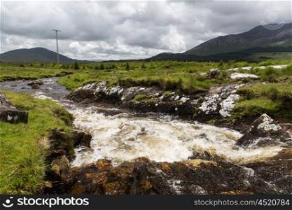 nature and landscape concept - view to river rapids and hills or mountains at connemara in ireland. view to river and hills at connemara in ireland