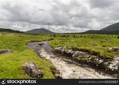 nature and landscape concept - view to river rapids and hills or mountains at connemara in ireland. view to river and hills at connemara in ireland