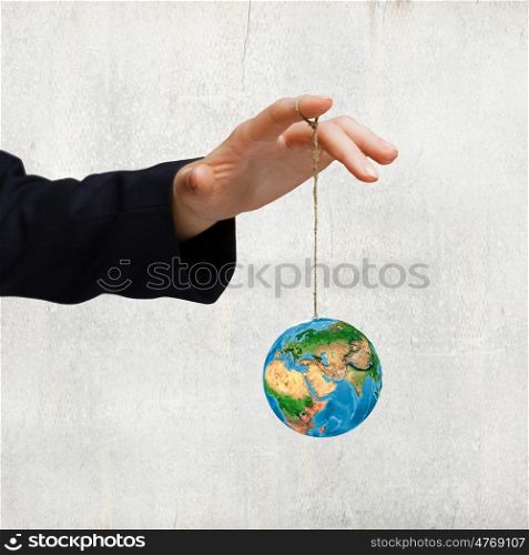 Nature and mankind. Close up of human hand holding Earth planet on rope. Elements of this image are furnished by NASA