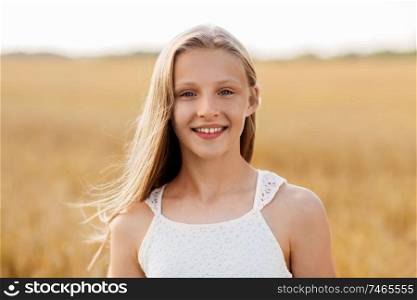 nature and people concept - smiling young girl on cereal field in summer. smiling young girl on cereal field in summer