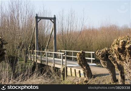 nature area in holland with willows and wooden drawbridge and small river