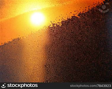 Nature background with bright sunlight, water drops and ice pattern on winter window glass