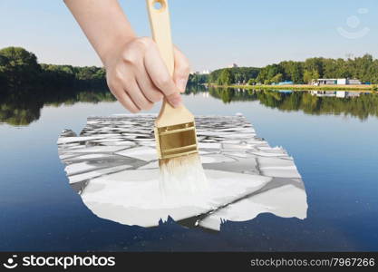 nature concept - seasons and weather changing: hand with paintbrush paints ice floe in summer river