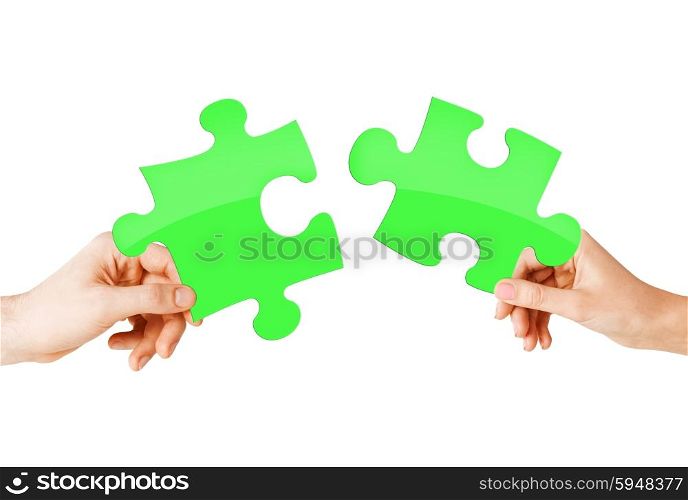 nature, ecology, energy saving and people concept - close up of couple hands trying to connect green puzzle pieces