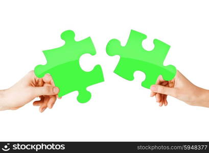 nature, ecology, energy saving and people concept - close up of couple hands trying to connect green puzzle pieces