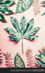 Nature flat lay with tropical plants and leaves on pastel pink background, top view