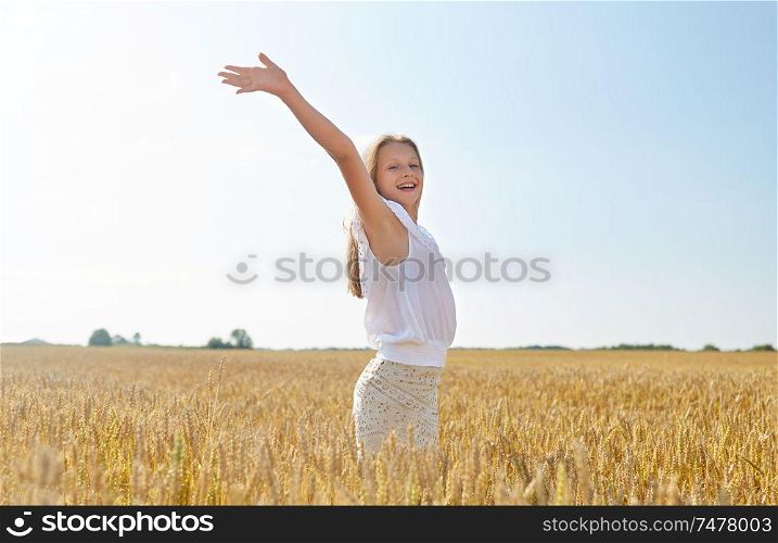 nature, harvest and freedom concept - happy young girl with hands outstretched on cereal field in summer. happy smiling young girl on cereal field in summer