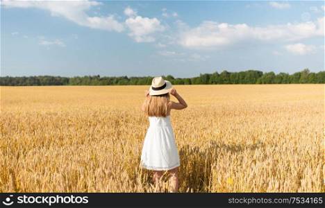 nature, harvest and people concept - portrait of smiling young girl in straw hat on cereal field in summer. portrait of girl in straw hat on field in summer