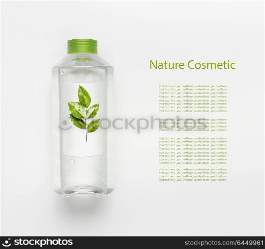 Nature herbal cosmetic concept. Transparent liquid bottle of toner, micellar water or cleansing product with green leaves and branding mock up on white desk background , top view.