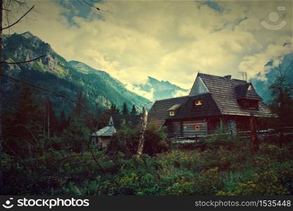 Nature in mountains. Old wooden house in beautiful mountains scenery. Vintage picture.