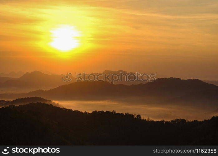 Nature landscape background beautiful view of the morning fog filling the valleys of smooth hills mountain range layer yellow forest sunrise and sunset in mountains with orange sky dramatic