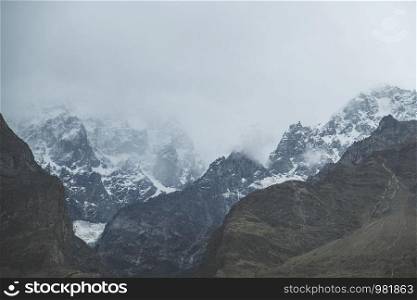 Nature landscape view of clouds and fog covered snow capped Ultar Sar mountain in Karakoram range, Hunza valley. Gilgit Baltistan, Pakistan.